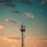 A communication tower silhouetted against a colorful sunset sky in Cruzeiro, Brazil.
